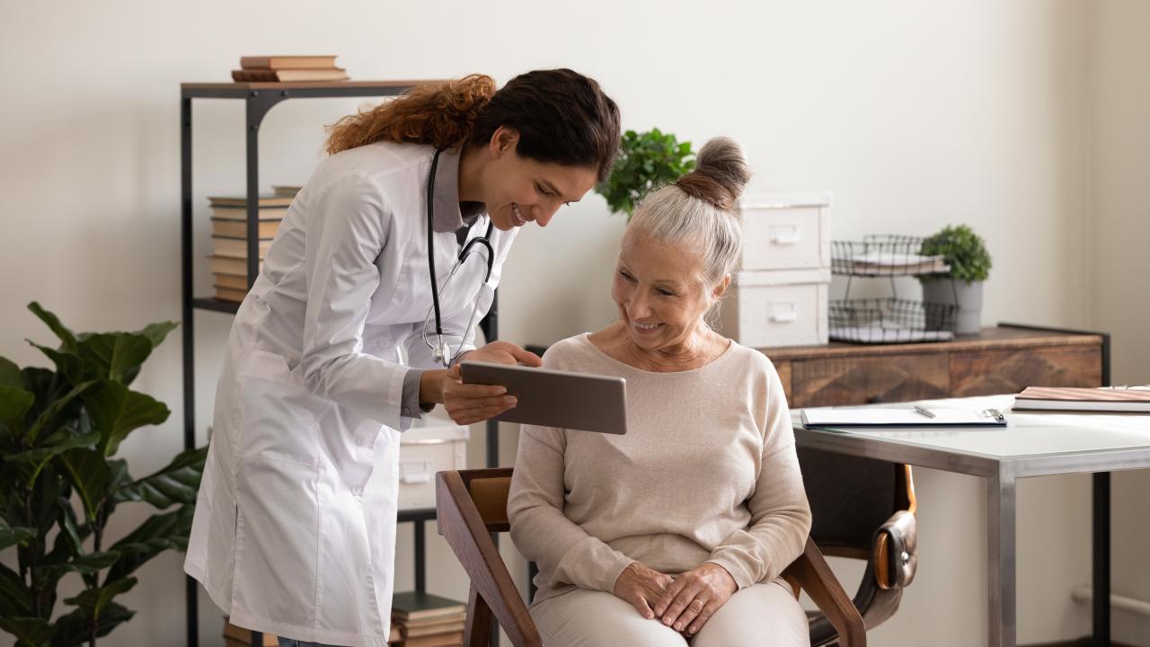 A female doctor is showing a screen and explaining some infomation to a senior patient 