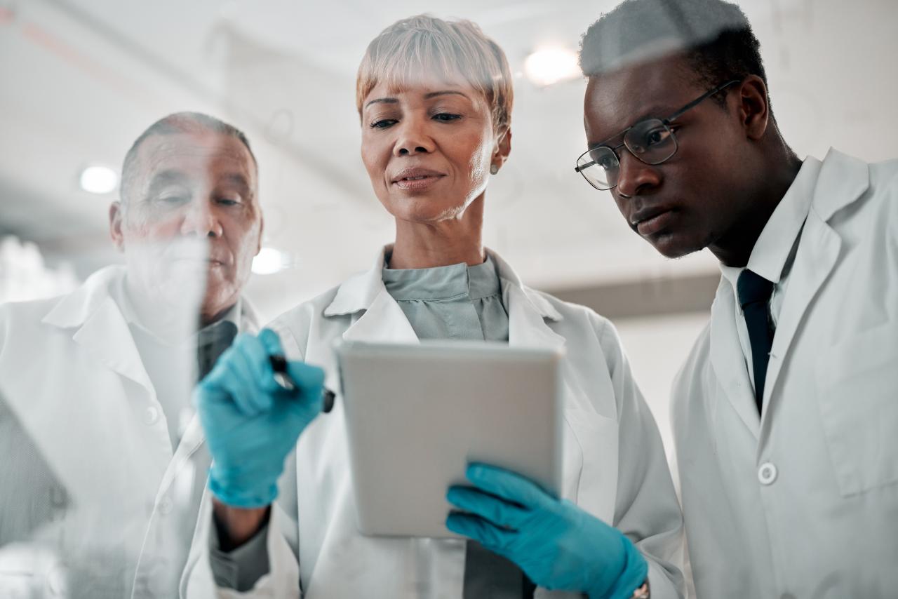 three doctors are looking at a pad screen